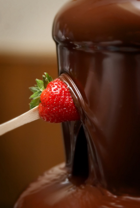 strawberry being dipped into chocolate fountain