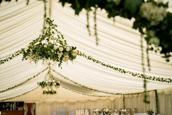 Floral chandeliers and ivy garlands in marquee